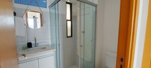 A bathroom with a glass shower enclosure, a sink with a mirror, and a toilet. - COITP0100 - Condomínio Mar de Itapuã (Salvador)