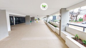 Ein Korridor mit Fliesenboden, einem grünen Fluchtzeichen und einem Logo an der Decke.