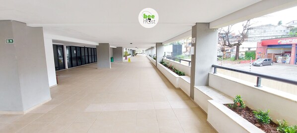 A corridor with a tiled floor, glass doors, and a view of the street outside. - COITP0100 - Condomínio Mar de Itapuã (Salvador)
