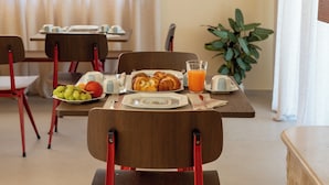 Une table de petit-déjeuner avec des croissants, des fruits et du jus d’orange.