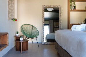 A bedroom with a large bed, a green chair, a small table with a plant, and a mirror with an ornate frame. - Radici d'Olivo (Bisceglie)