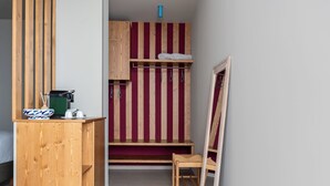 Une petite pièce, de taille modeste, avec un bureau en bois, une chaise, un lit et un mur à rayures.