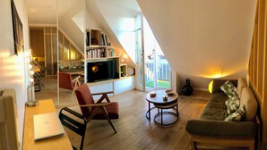 Een modern loft appartement met een hoogslaper, een bank, een eettafel en een televisie.