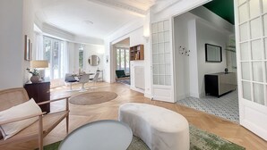 A spacious living room with a large window, a dining area, and a green rug.