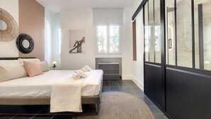 A modern bedroom with a large bed, a bedside table, a mirror, and a wardrobe.