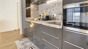 Eine moderne Küche mit Marmorfliesenspiegel, Edelstahlgeräten und einem eingebauten Backofen.