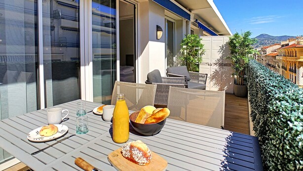 Ein Balkon mit einem Frühstückstisch, komplett mit Orangensaft, Brot und einem Gebäck.
