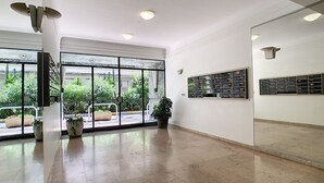 Eine geräumige Lobby mit einer großen Glasdoor, die zu einem Außenbereich führt, einer Zimmerpflanze und einem wandmontierten Ausstellungsfach.