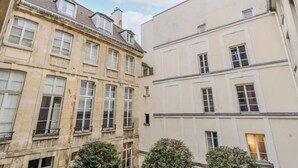 A multi-story building with a classic architectural style, featuring symmetrical windows and a central entrance. - Magnificent duplex in the Marais district (Paris)
