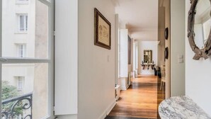 A corridor with a marble bench, a framed picture, and a mirror on the wall. - Magnificent duplex in the Marais district (Paris)