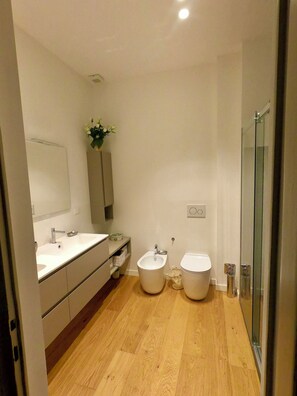 Een moderne badkamer met een ruime wastafel, een toilet en een bidet.