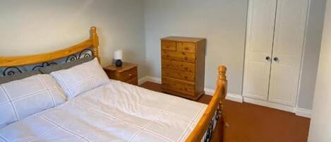 A bedroom with a wooden bed, a nightstand, a dresser, and a wardrobe.