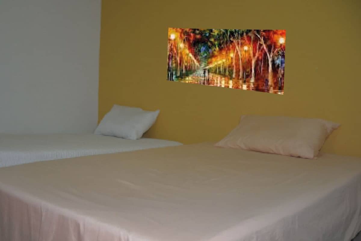 A hotel room with two beds, each with a white bedspread and pillows.