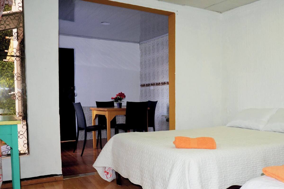 A bedroom with a bed, a small table with chairs, and a painting on the wall.