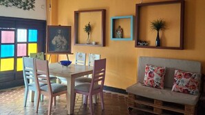 Un comedor con mesa y sillas, ventilador de techo y un sofá con cojines.