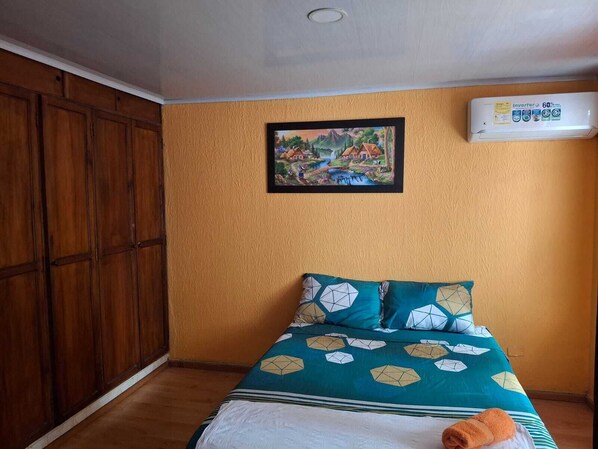 Un dormitorio con cama, un cuadro y un equipo de aire acondicionado.
