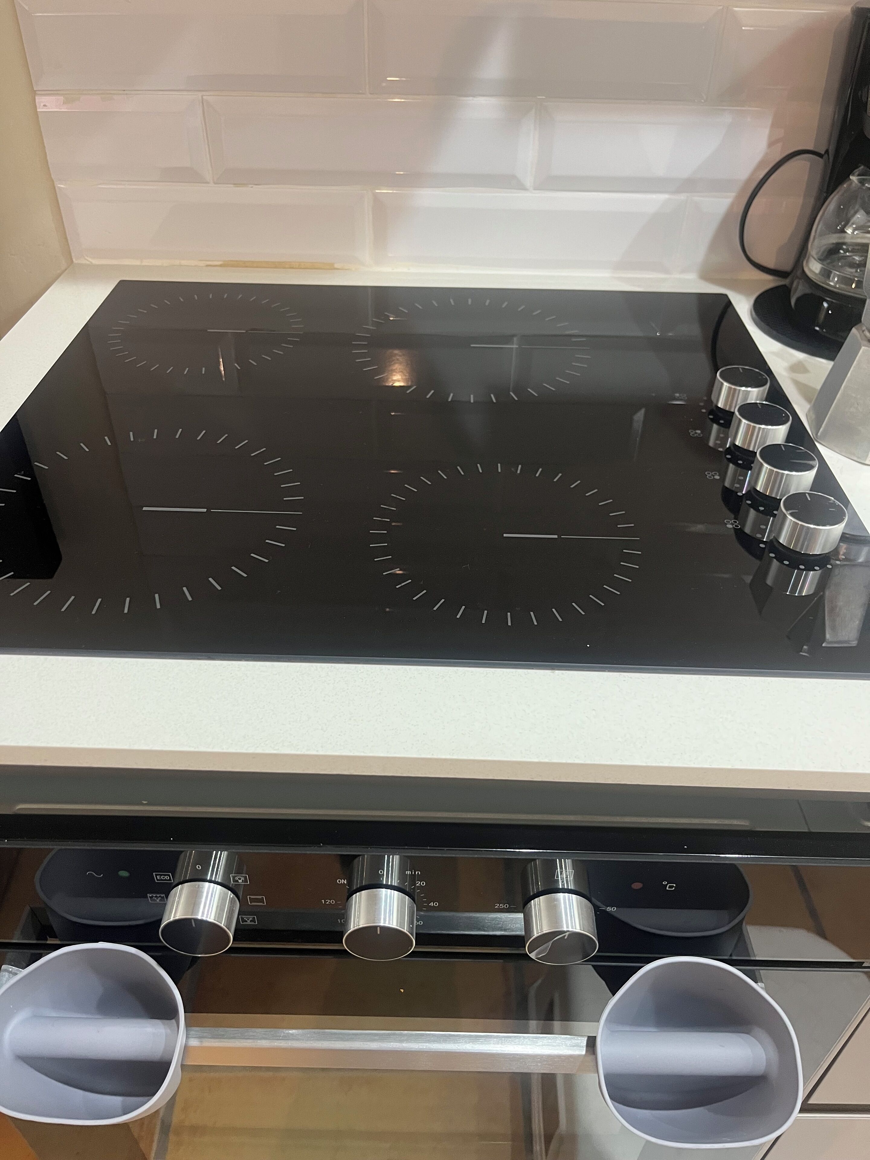 A kitchen with a black stovetop, four burners, and a stainless steel range hood.