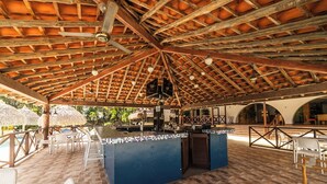 An outdoor bar area with a tiled floor, wooden ceiling beams, and a blue counter.