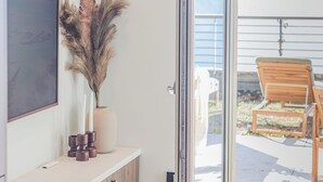 A room with a glass door leading to an outdoor area with a wooden chair and a view of the sky. - Aurora Apartment by Rent all Como (Como)