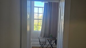 Ein Zimmer mit Fenster, einem kleinen Tisch und einem Stuhl.