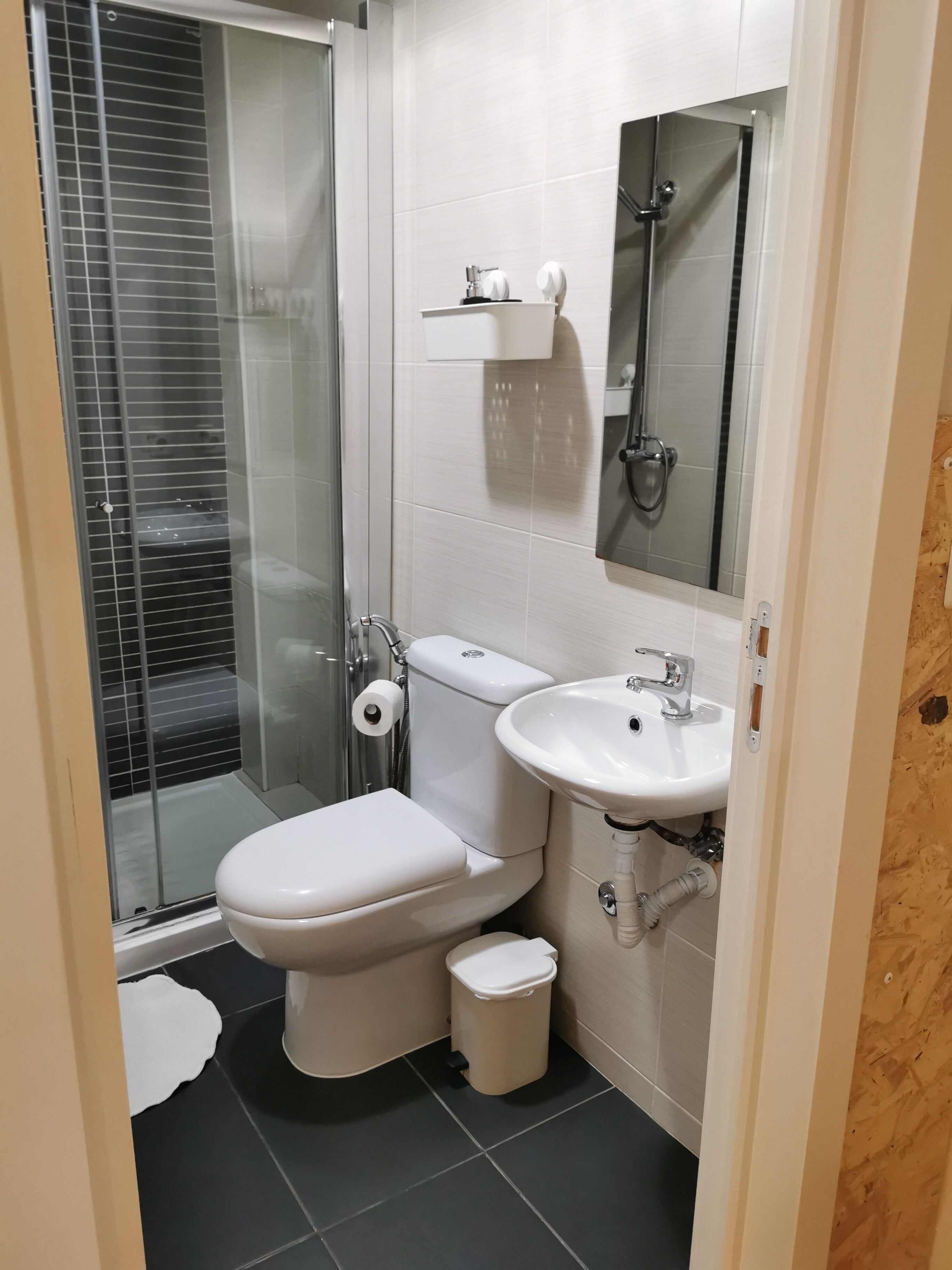 A compact bathroom with a toilet, sink, and shower.