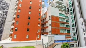 Un edificio residencial de varios pisos con balcones, piscina y vista a una torre.
