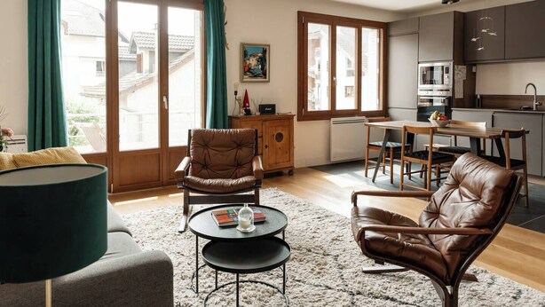 A modern living room with a sofa, two leather chairs, a coffee table, and a dining area with a table and chairs. - Welcome to Annecy!<br>Enjoy a comfortable stay in our bright apartment, located in a quiet residential area. Just a 10-minute walk from the train station and the historic center, and 20 minutes from the lake — the perfect location to explore the city (Sévrier)