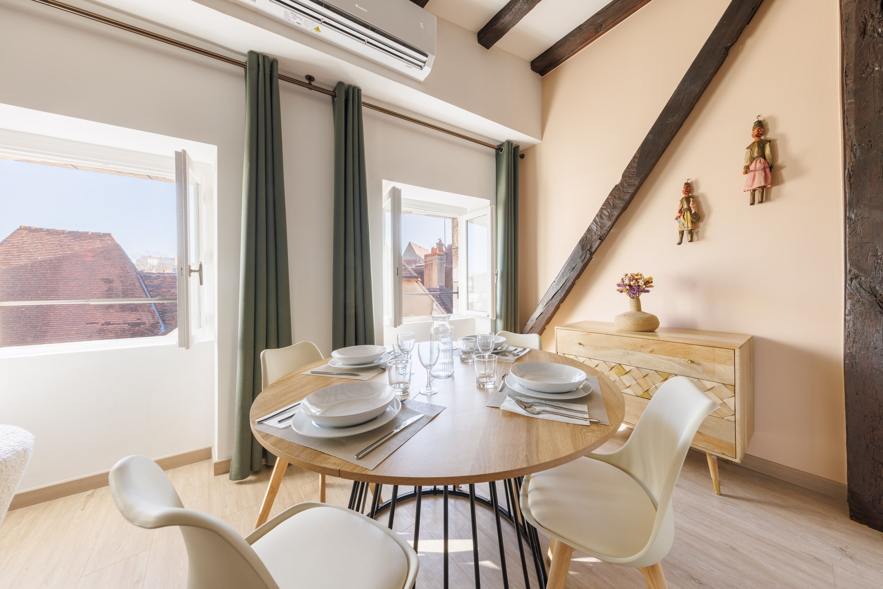 Een eethoek met een houten tafel gedekt voor vier personen, een houten kast en een uitzicht op de stad door grote ramen.