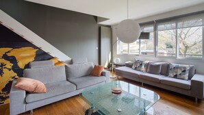 Ein modernes Wohnzimmer mit einem grauen Sofa, einem Glastisch und einer großen Weltkarte an der Wand.