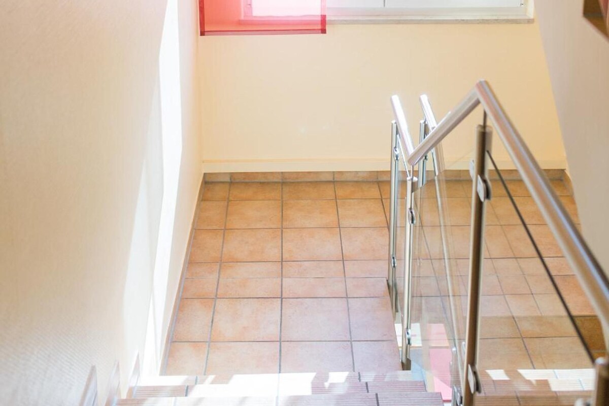 A staircase with metal railings leading to a landing with a window.