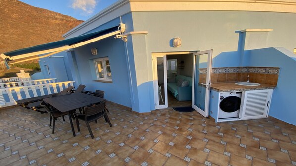 A patio with a table and chairs, a washing machine, and a door leading to a room. - Molino azul 6A (Valle Gran Rey)