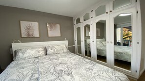 Un dormitorio con cama, armario y dos cuadros en la pared.