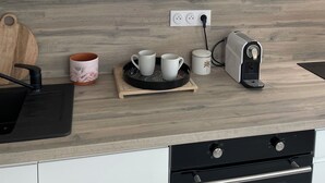 A modern kitchen with white cabinets, a wooden countertop, a coffee maker, a toaster, and a cutting board.