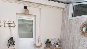 A cozy room with wicker furniture, a small table with a vase, and a door with a mirror.