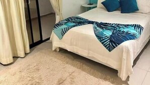 A bedroom with a bed, a nightstand, a lamp, a ceiling fan, and a sliding door. - Wind Chimes-Condo in Cabarete DR (Cabarete)