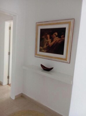 Un pasillo con un cuadro enmarcado en la pared y un pequeño cuenco decorativo debajo.