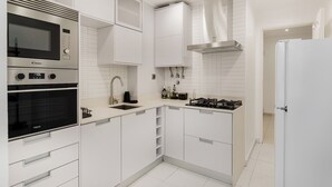 A modern kitchen with white cabinetry, a built-in microwave, oven, and gas stove. - Luz & Mar at Coastal Oeiras (Oeiras)