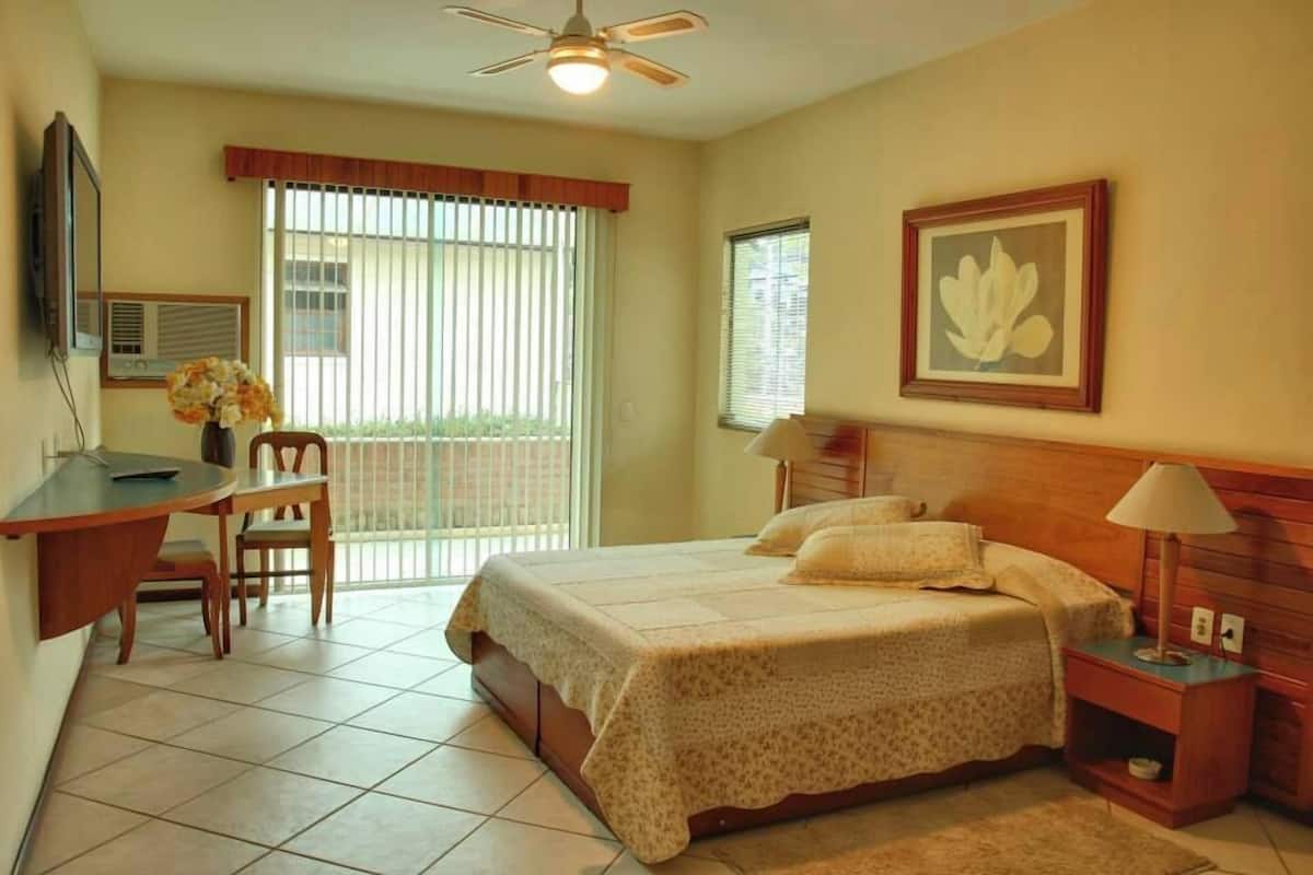 A bedroom with a bed, bedside tables, a desk, and a chair.