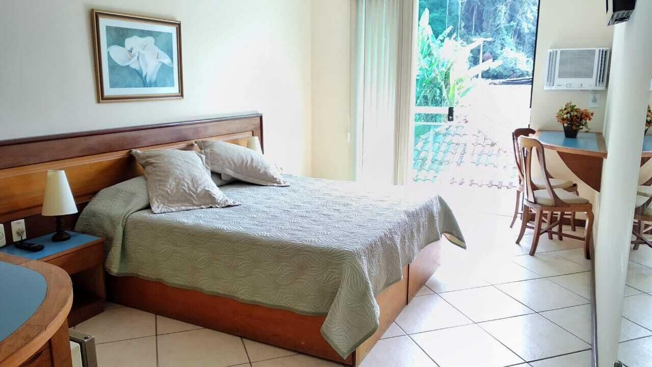 Une chambre à coucher avec un lit, une table de chevet, une lampe et une vue sur l’extérieur.