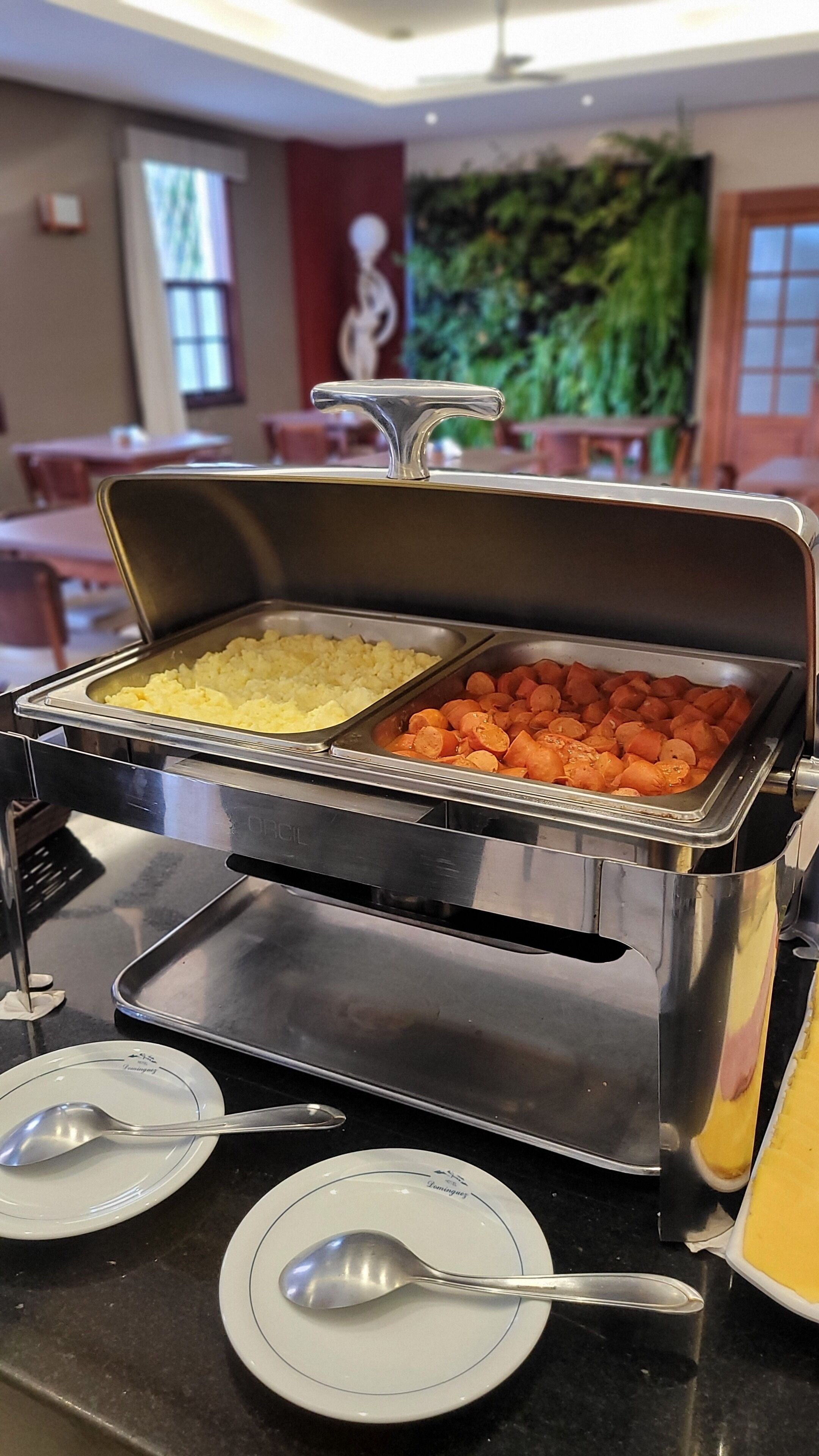 A buffet setup with two trays of food, one with scrambled eggs and the other with carrots.
