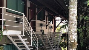 A building with a stone-paved entrance, a white staircase with metal railings, and a tree with broad leaves. - Hotel Dominguez Plaza (Nova Friburgo)