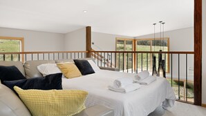 Ein Schlafzimmer mit Bett, Sofa und einem Balkon mit Blick ins Freie.