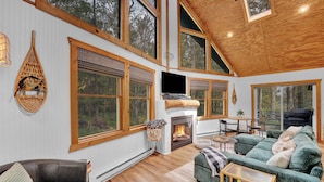 A spacious living room with a fireplace, large windows, and a cozy seating area.