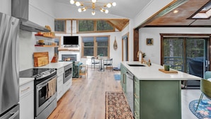 A modern kitchen with a central island, built-in appliances, and a large window overlooking the outdoors.