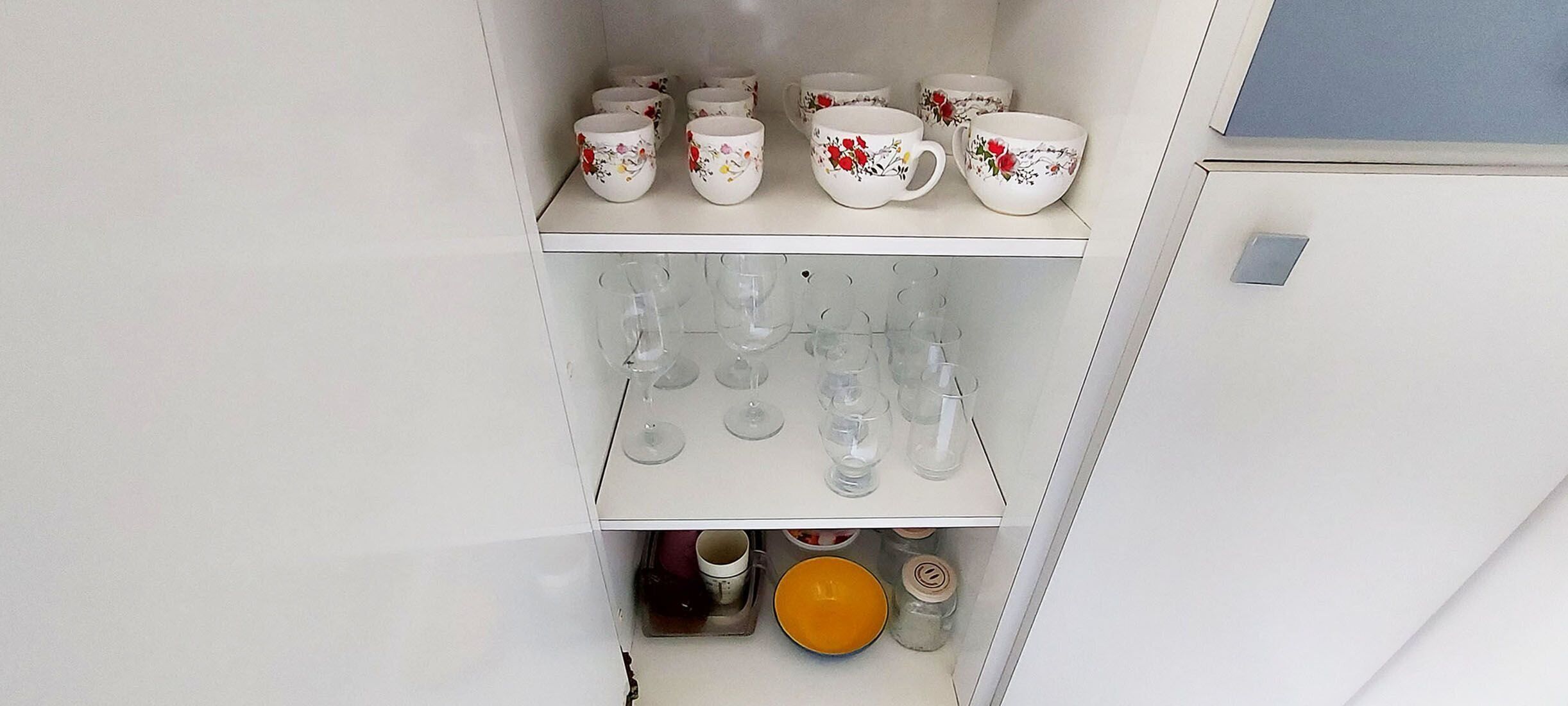 Eine Küche mit weißen Schränken, einer weißen Arbeitsplatte und einem weißen Kühlschrank.