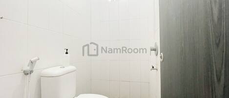 A bathroom with a toilet, a shower, and a sink.