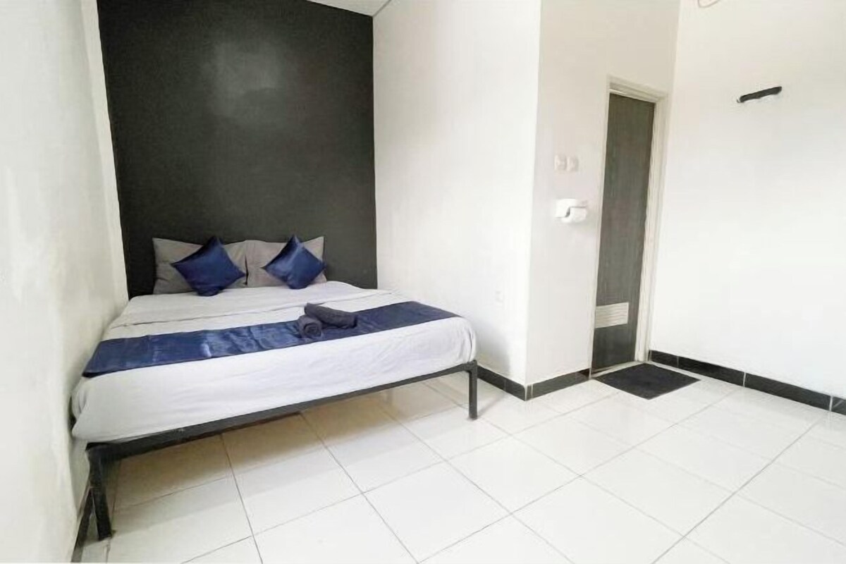 A single bed with a white mattress and blue bedding, a dark headboard, and a tiled floor.