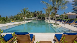 Piscina com espreguiçadeiras azuis e palmeiras.