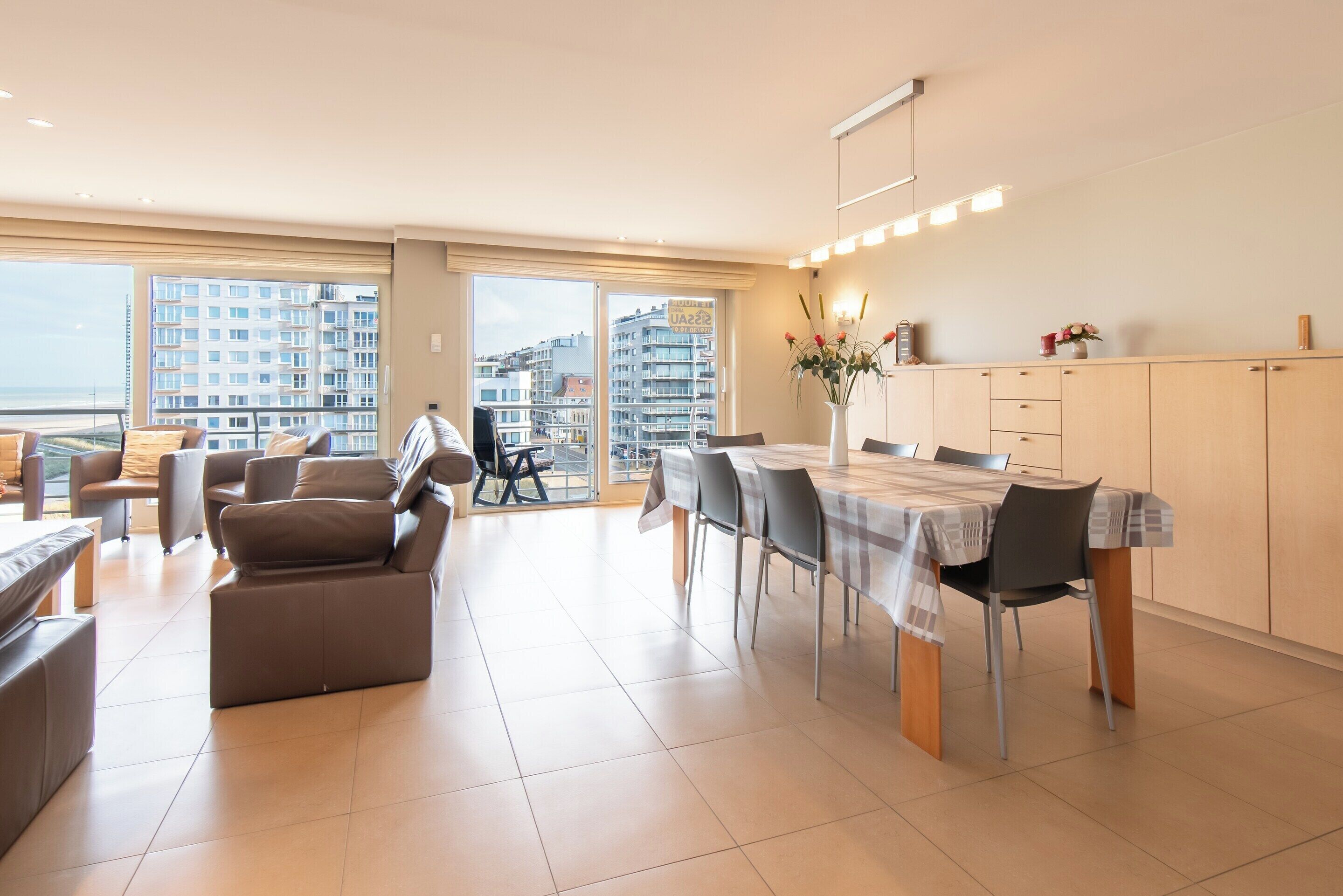 A modern apartment with a dining area, a sofa, and a view of the city.