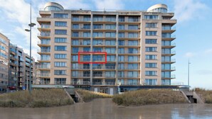 A multi-story hotel with a central atrium, outdoor access, and a view of the beach.